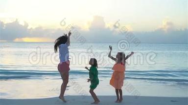 可爱<strong>的</strong>小女孩和年轻<strong>的</strong>母亲在热带海滩在<strong>温暖的</strong>晚上跳舞和乐趣。 日落时分<strong>的家</strong>人